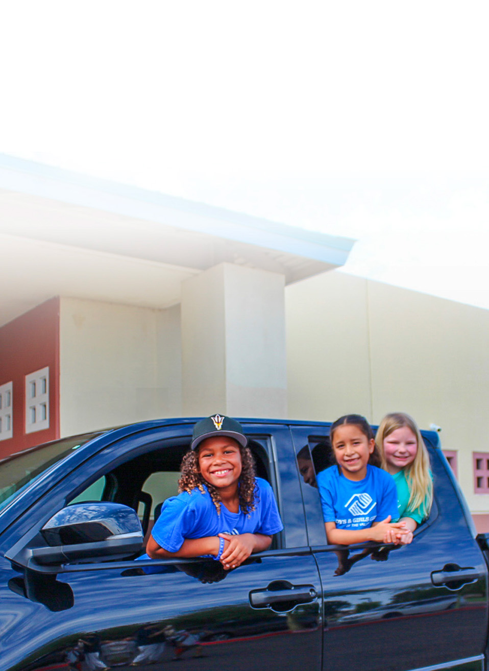 Three BGCAZ girls smiling out of a truck